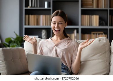 Excited Woman Looking At Laptop Screen, Screaming With Joy, Surprised By Message With Good News, Overjoyed Young Female Sitting On Couch At Home, Using Computer, Celebrating Online Win Or Success