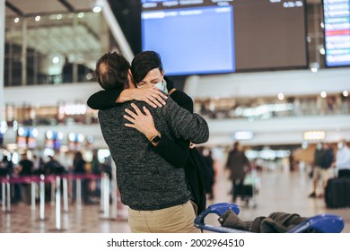 Excited Woman Meeting Husband During Pandemic At Airport Arrival Gate. Man Giving Warm Hug To His Wife On Arrival At Airport In Pandemic.