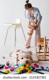 Excited Woman Playing With Son Near Rocking Horse And Toy Dog On White