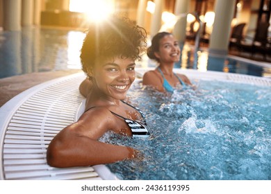 Excited woman, portrait and relax with water in jacuzzi at hotel, resort or hot tub spa together. Happy female person or friends with smile for relaxation, hospitality or heated bath by indoor pool - Powered by Shutterstock