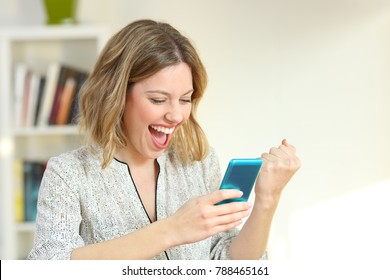 Excited Woman Reading Online Smart Phone Content At Home