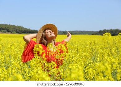 Excited woman in red spreading stretching arms in a yellow flowered field