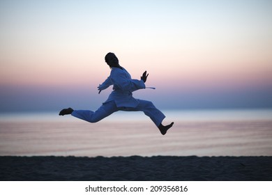 Excited woman silhouette jumping at sunset