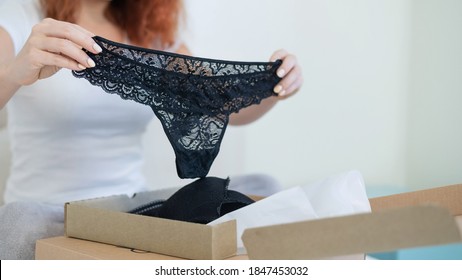 An excited woman unpacks a delivered order. Online shopping for lingerie at home