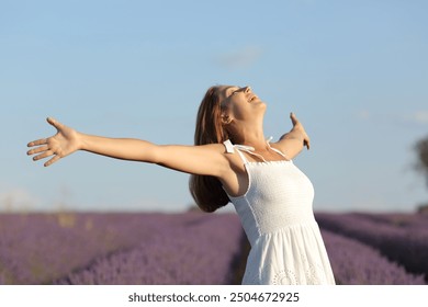 Excited woman wearing white dress celebrating in lavender field a sunny day - Powered by Shutterstock