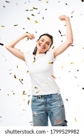 Excited Woman In White T-shirt With Hands Above Head Near Confetti On White