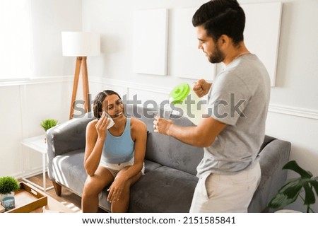 Excited woman wiping her sweat because of the hot weather while her boyfriend brings cold lemonade 