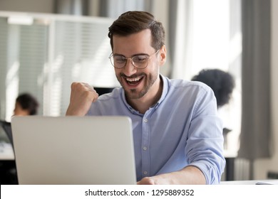 Excited worker sitting at desk in coworking space use computer reading message looking at device screen received great unbelievable opportunity or reward. Motivated employee celebrating job promotion - Powered by Shutterstock