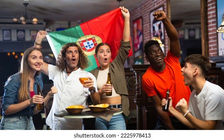 Excited young adult football fans having fun in sports bar, celebrating victory of favorite Portuguese team together after watching match - Powered by Shutterstock