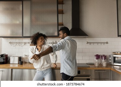 Excited Young African American Couple Have Fun Enjoy Early Morning In Modern Renovated Kitchen. Happy Millennial Biracial Man And Woman Dance Celebrate Moving Relocation To Own Home. Realty Concept.