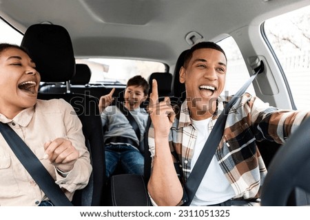Excited young african american family singing riding new car and having fun enjoying summer road trip on vacation