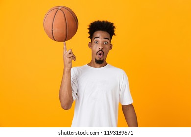 Excited young african man in t-shirt standing isolated over yellow background, playing basketball - Powered by Shutterstock