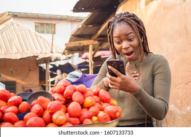 Excited Young African Woman In A Local African Market Viewing Content On Her Phone Feeling Surprised