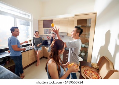 Excited Young Asain People Looking At Their Friend Juggling With Orangers At Home Party