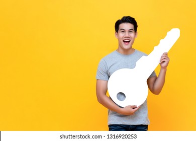 Excited Young Asian Man Holding Big Mockup Car Key Studio Shot In Yellow Backround With Copy Space