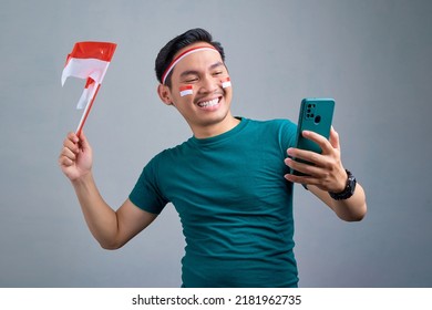 Excited young Asian man holding mobile phone and indonesian flag while celebrating indonesia independence day isolated on grey background. indonesia independence day celebration concept - Powered by Shutterstock