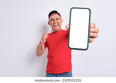 Excited young Asian men celebrate Indonesian independence day on 17 August while holding smartphone with blank screen isolated over white background