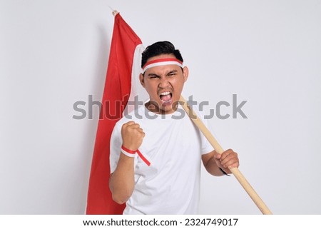 Excited young Asian men celebrate Indonesian independence day on 17 August by holding the Indonesian flag isolated over white background