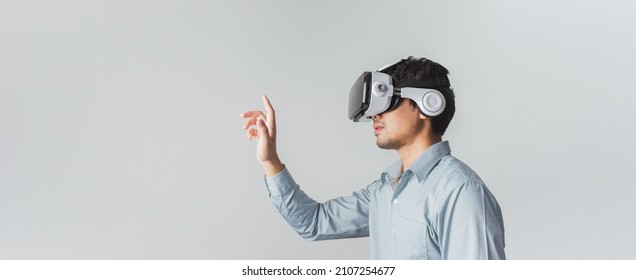 Excited young Asian wearing VR headset with hand pointing to space on web banner grey background.