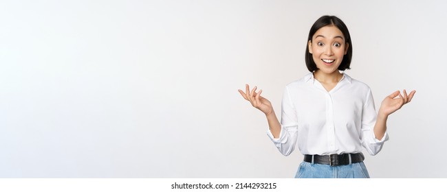 Excited young asian woman, looking happy in disbelief, hear surprising news, amazing info, standing over white background - Shutterstock ID 2144293215
