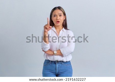 Excited young Asian woman pointing finger up with great new idea isolated over white background