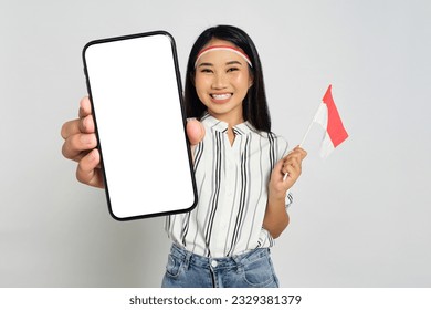 Excited young Asian women celebrate Indonesian independence day while holding smartphone with blank screen and Indonesian flags isolated on white background - Powered by Shutterstock