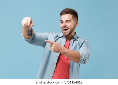 Excited Young Bearded Guy 20s In Casual Shirt Posing Isolated On Pastel Blue Wall Background Studio Portrait. People Emotions Lifestyle Concept. Mock Up Copy Space. Pointing Index Finger On Car Keys