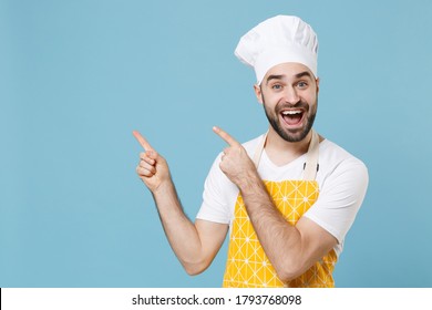 Excited young bearded male chef or cook baker man in apron white t-shirt toque chefs hat isolated on pastel blue wall background studio portrait. Cooking food concept. Pointing index fingers aside up - Shutterstock ID 1793768098