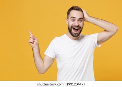 Excited Young Bearded Man Guy In White Casual T-shirt Posing Isolated On Yellow Background Studio Portrait. People Lifestyle Concept. Mock Up Copy Space. Pointing Index Finger Up, Put Hand On Head