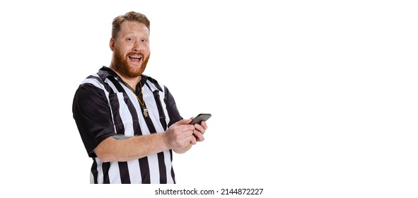 Excited young bearded man, soccer or football referee using phone isolated on white studio background. Concept of sport, rules, competitions, rights, ad, sales. Flyer with copy spcae for text