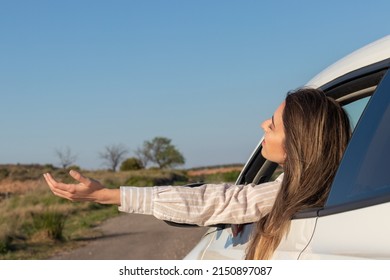 Excited Young Beautiful Woman Looking Out The Car Window Feeling The Air With Her Arms Raised In The Countryside