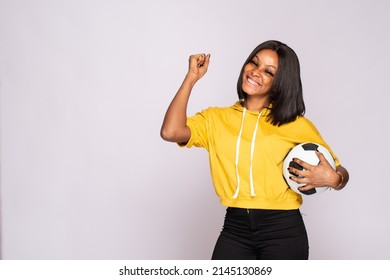 excited young black lady holding a soccer ball rejoicing