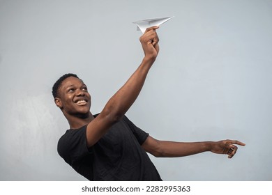 excited young black man holding a paper plane, travel concept