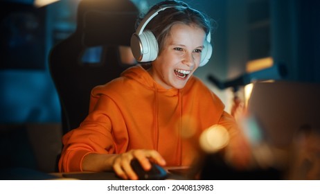 Excited Young Boy In Headphones Playing Video Games On Laptop Computer In Cozy Dark Room At Home. Happy Successful Teenager Beating Players And Winning At The Online Competition.