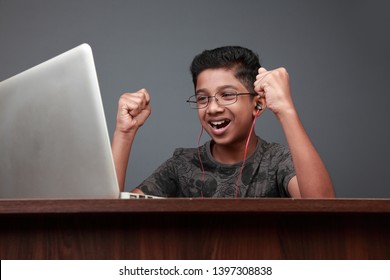 Excited young boy of Indian origin using laptop