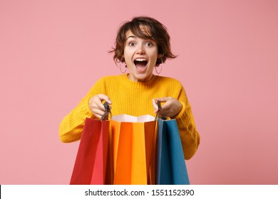 Excited young brunette woman girl in yellow sweater posing isolated on pink wall background in studio. People lifestyle concept. Mock up copy space. Holding package bag with purchases after shopping - Shutterstock ID 1551152390