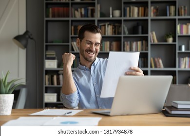 Excited young Caucasian man work on computer feel euphoric reading paper letter correspondence. Happy overjoyed male worker triumph with good pleasant news message in postal paperwork notice. - Shutterstock ID 1817934878