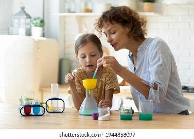 Excited young Caucasian mother and little 9s daughter have fun play with chemistry lab game together. Caring playful mom and small teen girl child engaged in interesting scientific activity at home.