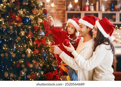 Excited young family making Xmas tree together at home, getting ready before Christmas Eve, copy space - Powered by Shutterstock