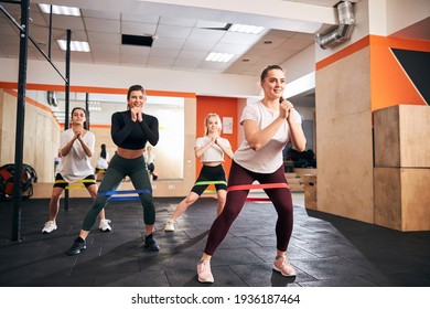 Excited young female athletes keeping themselves in shape by regular exercising with resistance bands - Shutterstock ID 1936187464