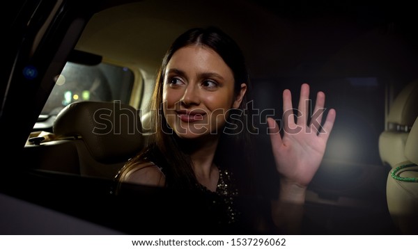 Excited young female star greeting public and\
photographers from car,\
fame