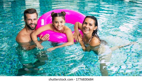 Excited And Young Happy Family On Vacation In The Spa Hotel Are Relaxing And Have Fun In The Swimming Pool. Summer Rest