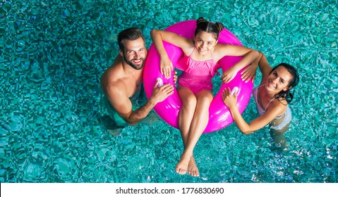 Excited And Young Happy Family On Vacation In The Spa Hotel Are Relaxing And Have Fun In The Swimming Pool. Summer Rest