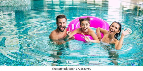 Excited And Young Happy Family On Vacation In The Spa Hotel Are Relaxing And Have Fun In The Swimming Pool. Summer Rest