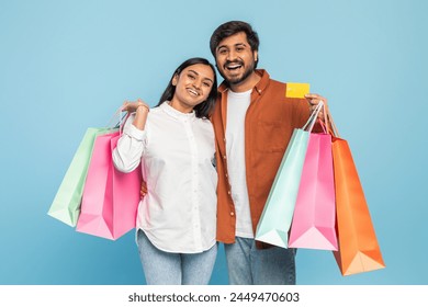 Excited young Indian couple with colorful shopping bags, expressing pleasure from a successful shopping spree - Powered by Shutterstock