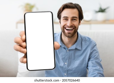 Excited Young Man Demonstrating Smartphone With Big Blank White Screen At Camera, Handsome Smiling Millennial Guy Showing Copy Space For Mobile App Advertisement, Sitting On Couch At Home, Mockup - Shutterstock ID 2057026640