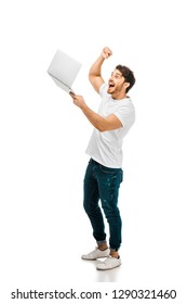 Excited Young Man Holding Laptop And Shaking Fist Isolated On White