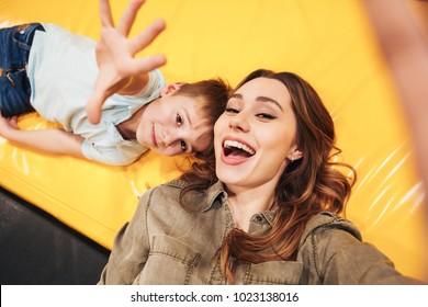 Excited young mother playing with her little son at the entertainment centre together and taking a selfie - Powered by Shutterstock