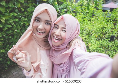 Excited Young Muslim Girl Friends Taking Selfie Together Outdoor