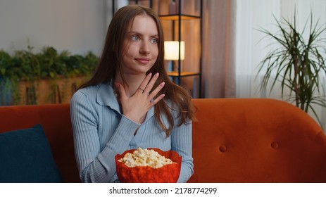 Excited Young Pretty Woman Sitting On Sofa Eating Popcorn And Watching Interesting Tv Serial, Sport Game, Film, Online Social Media Movie Content Online At Home. Girl Enjoying Domestic Entertainment